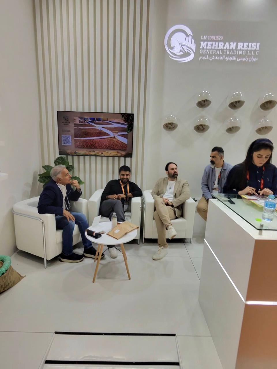 Visitors meeting at the MRGT stand beneath the Mehran Reisi company sign